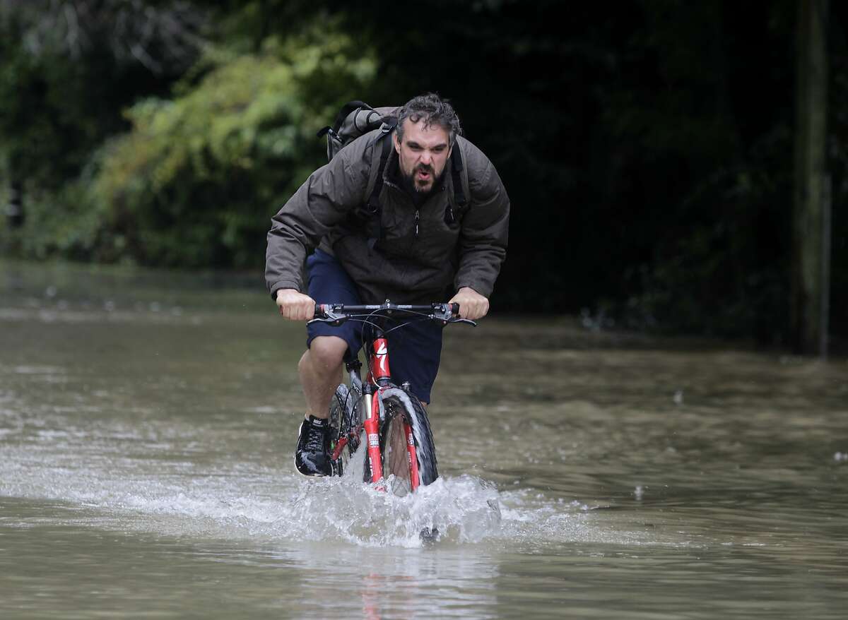 Corey Weaver pedals through flood waters as the Russian River surges in Guerneville, Calif. on Friday, Dec. 12, 2014.