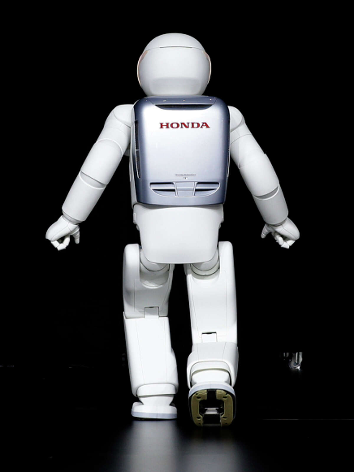Almost human: Honda’s robot, Asimo, can run forward and backward and hop on one foot. The Asimo Robot walks behind a curtain at the New York International Auto Show in New York, Thursday, April 17, 2014. (AP Photo/Seth Wenig)