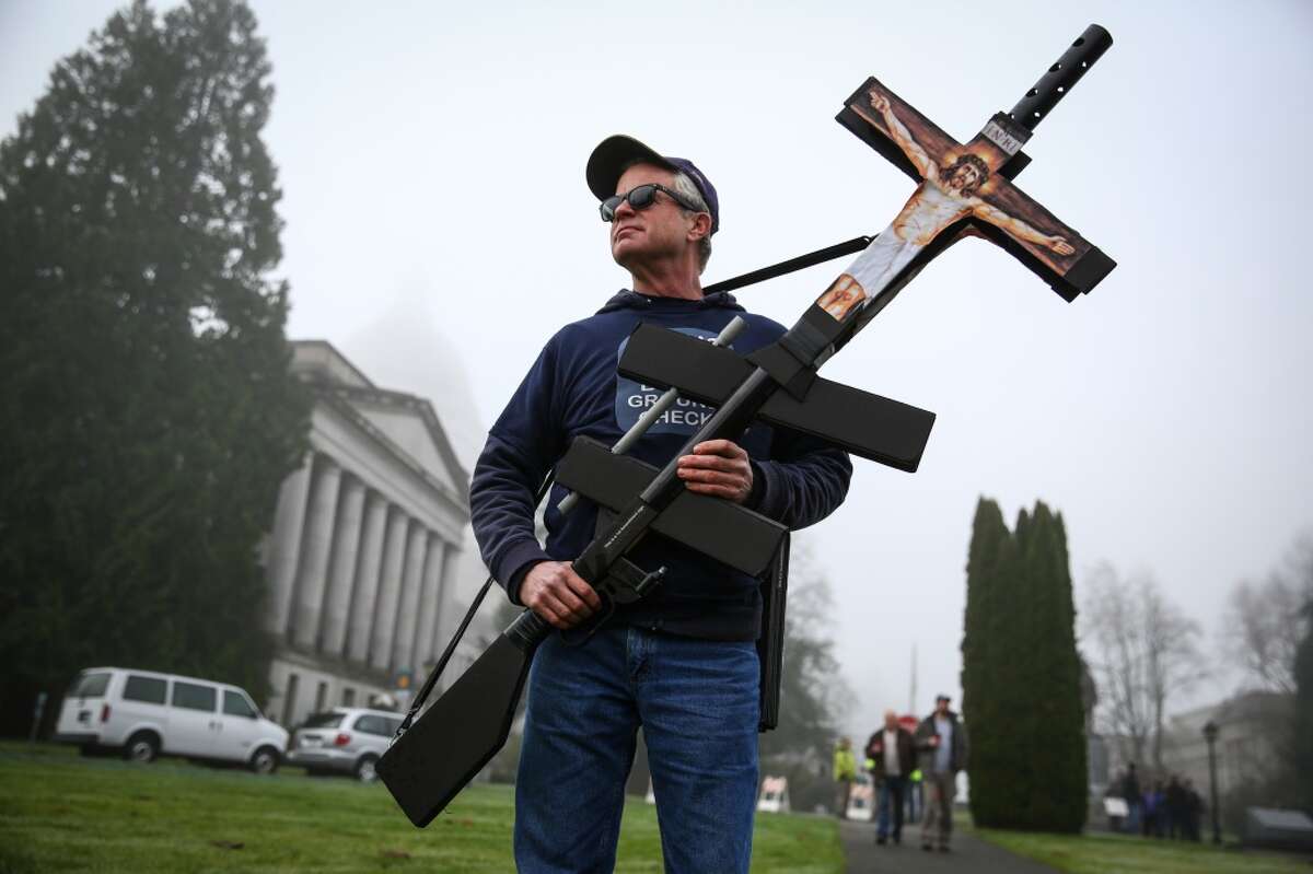 A man who wouldn't give his name, holds a prop as opponents of a Washington State law requiring mandatory background checks on all guns sales gather on the grounds of the State Capitol in Olympia. The law, known as Initiative 594, was passed by voters in November. Photographed on Saturday, December 13, 2014. (Joshua Trujillo, seattlepi.com)