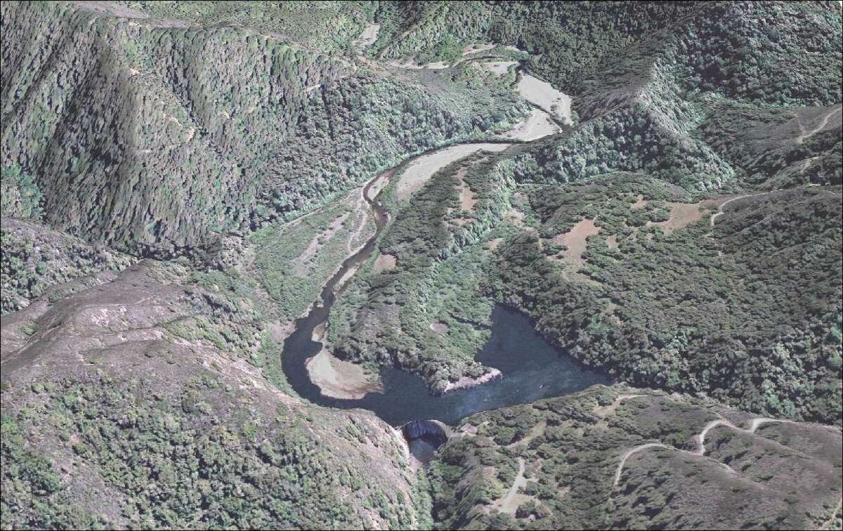 An aerial view of the San Clemente Dam, with the Carmel River and San Clemente Creek flowing into the silted over reservoir.