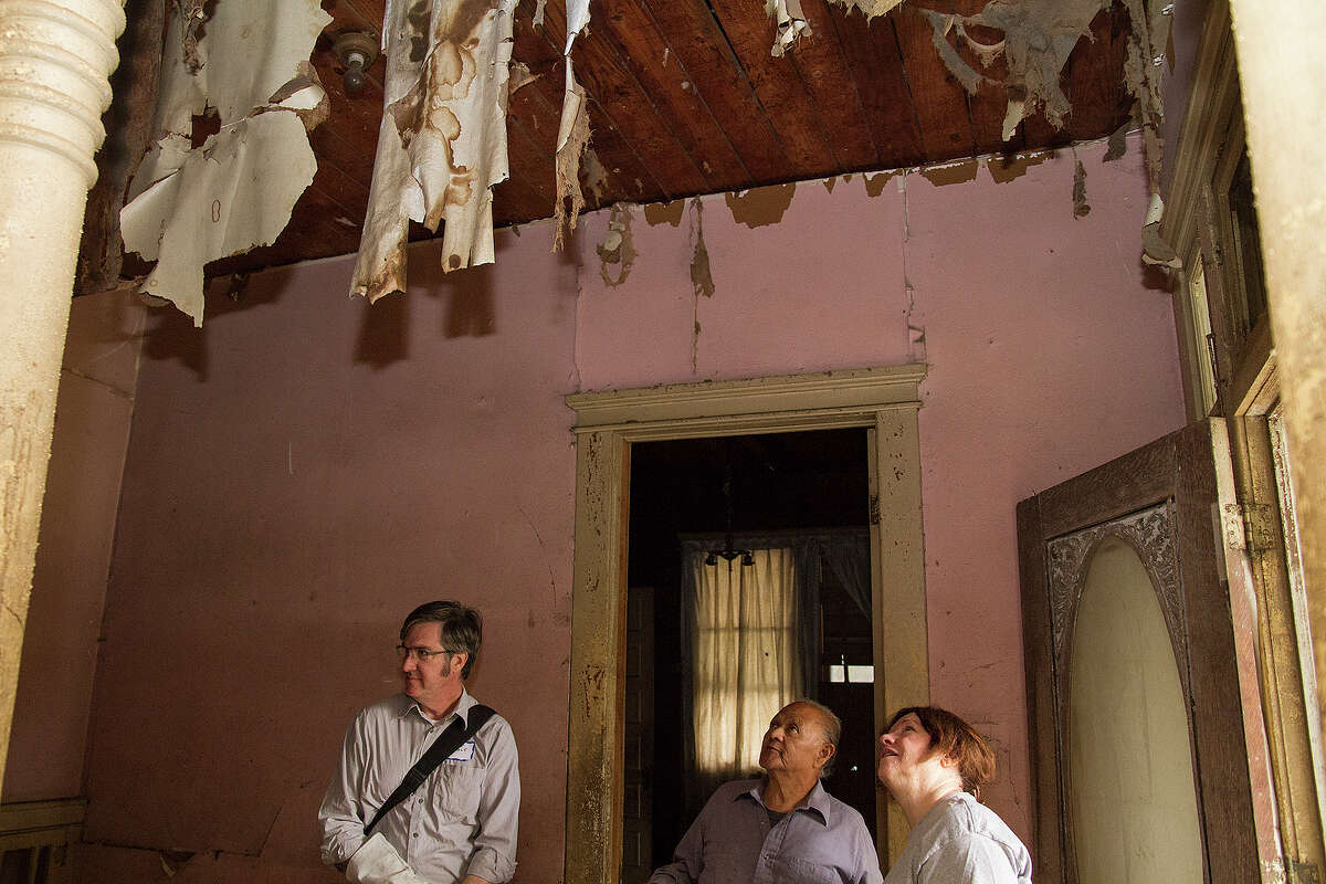 (Left to right) David Bogle, Miguel Calzada, and JoAnne Comeaux inspect the cheesecloth hanging from the ceiling in Calzada's home, Saturday, Dec. 13, 2014.
