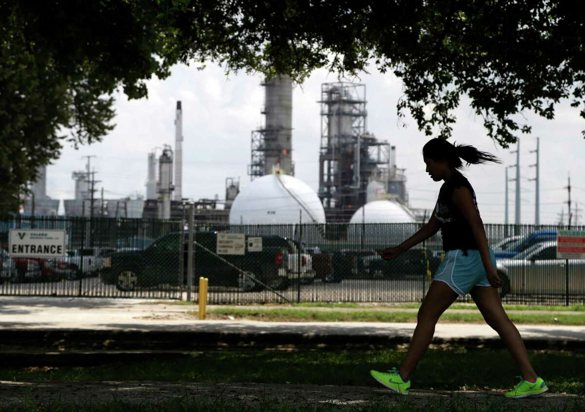 A teenage girl walks around the track of a park across the street from the Valero refinery Monday, Aug. 4, 2014, in the Manchester neighborhood of Houston. (AP Photo/Pat Sullivan)