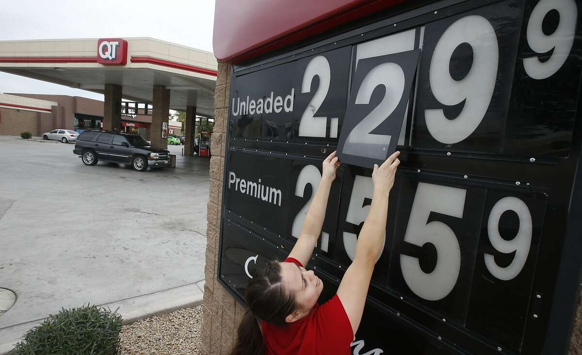 In this Friday, Dec. 12, 2014 photo, Quick Trip clerk Roxana Valverde adjusts the gas price sign numbers at a Tolleson, Ariz. QT convenience store as gas prices continue to tumble nationwide. The price of oil has fallen by nearly half in just six months, a surprising and steep plunge that has consumers cheering, producers howling and economists wringing their hands over whether this is a good or bad thing. (AP Photo/Ross D. Franklin)