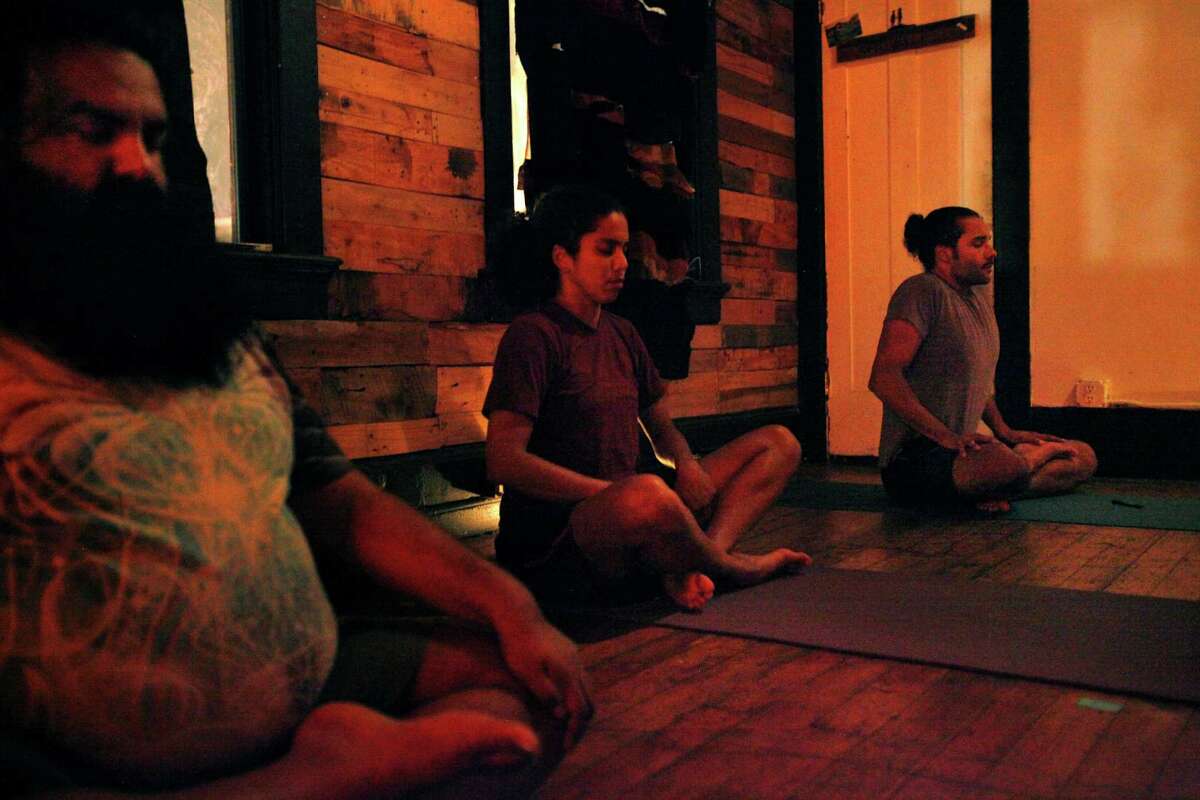 Praveen Sinha (left), Isamarie Perez and Nelson Sparks in the yoga class, which encourages students with a medicinal marijuana card to bring pot for personal consumption.