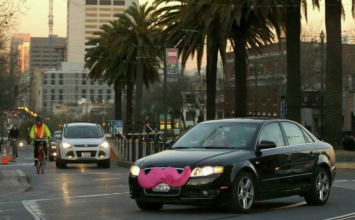 FILE - In this Jan. 17, 2013 file photo, a Lyft car drives crosses Market Street in San Francisco. California prosecutors have filed a lawsuit against Uber over the ridesharing company's background checks and other allegations, adding to the popular startup's worldwide legal woes. Meanwhile, San Francisco County District Attorney George Gascon said Tuesday, Dec. 4, 2014, that Uber competitor Lyft has agreed to pay $500,000 and change some of its business practices to settle its own lawsuit. (AP Photo/Jeff Chiu, File)