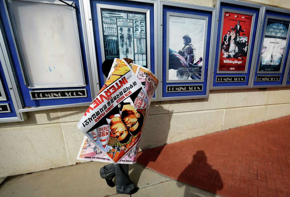 An Atlanta theater worker pulls down the poster promoting “The Interview.”