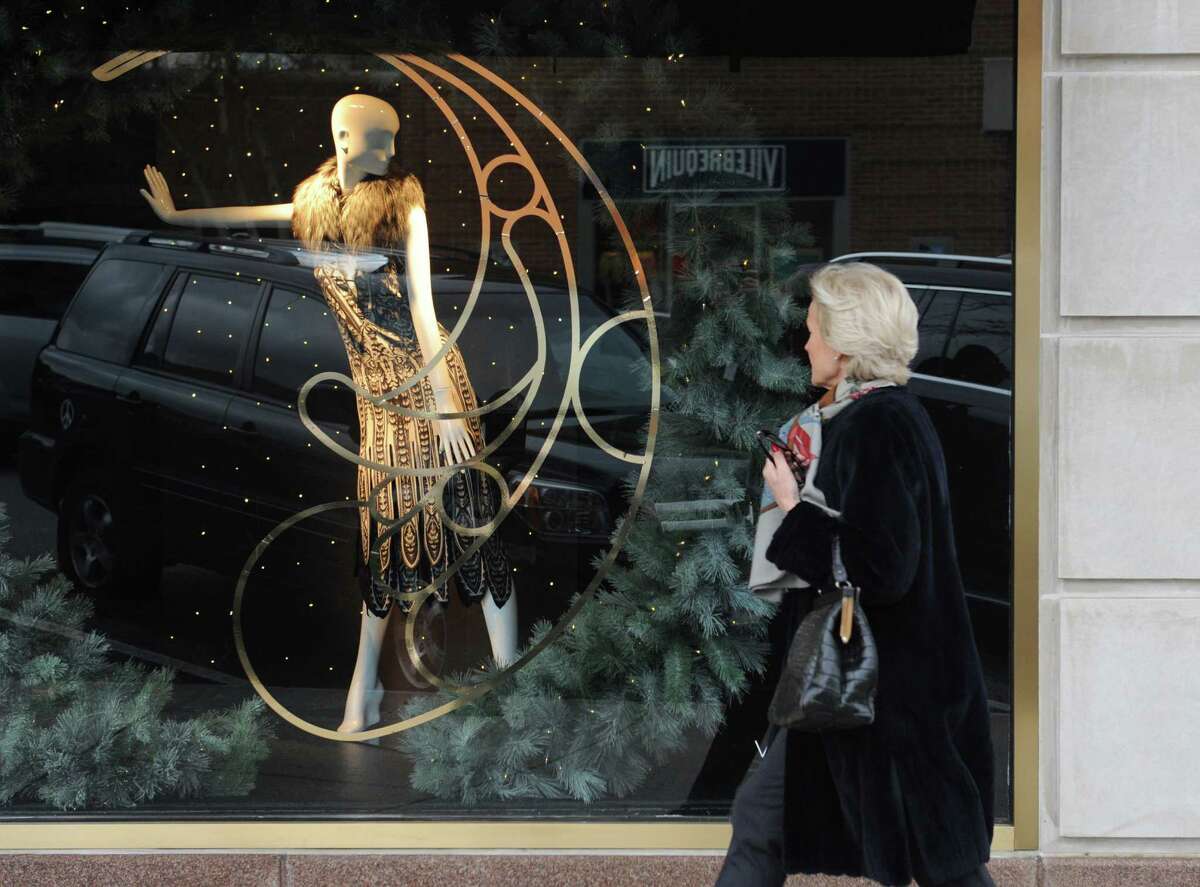 A fur-wearing mannequin in the window of Saks Fifth Avenue exchanges a glance with a woman walking along Greenwich Avenue in downtown Greenwich, Conn. Wednesday, Dec. 17, 2014.