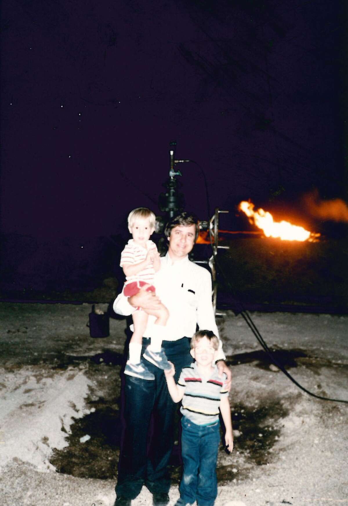 As a gas flare lights the scene, Larry Oldham stands with sons Cody, left, and Christoper, at a well site near Big Spring, Texas in 1986--around the time the bottom fell out of the Texas oil industry. Oldham founded Midland-based independent oil company Parallel Petroleum in 1979. (Photo courtesy Larry Oldham)