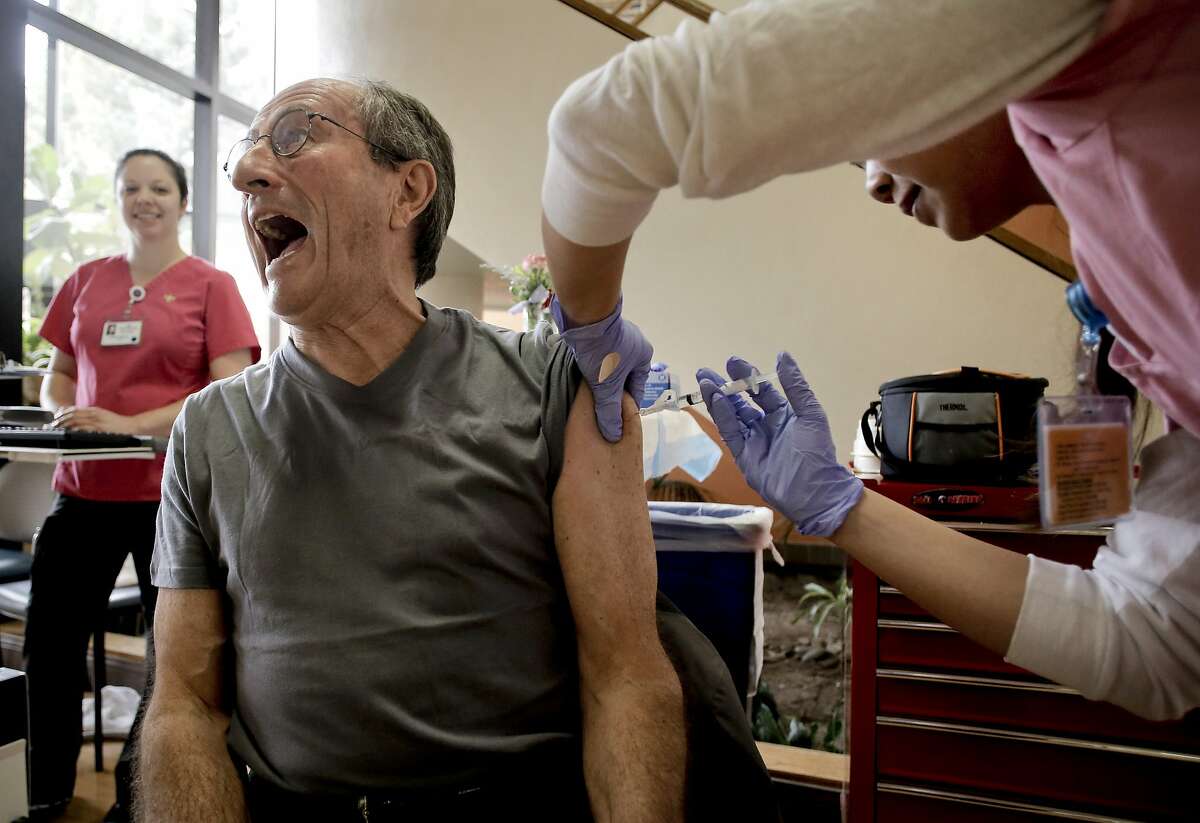 Pascal Jean Pierre, of Menlo Park, plays it up as he gets a flu shot from Ginny To, a LVN at the Kaiser Permanente flu clinic in Redwood City, Calif., on Thursday Dec. 18, 2014. Kaiser has already administered over one million flu shots in their Northern California facilities.