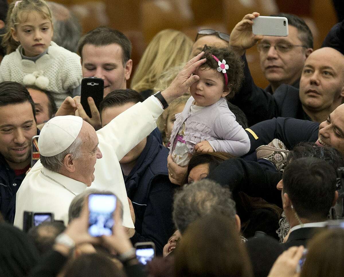 Pope Francis blesses a baby during an audience with the Holy See's employees in the Paul VI hall at the Vatican, Monday, Dec. 22, 2014. (AP Photo/Alessandra Tarantino)