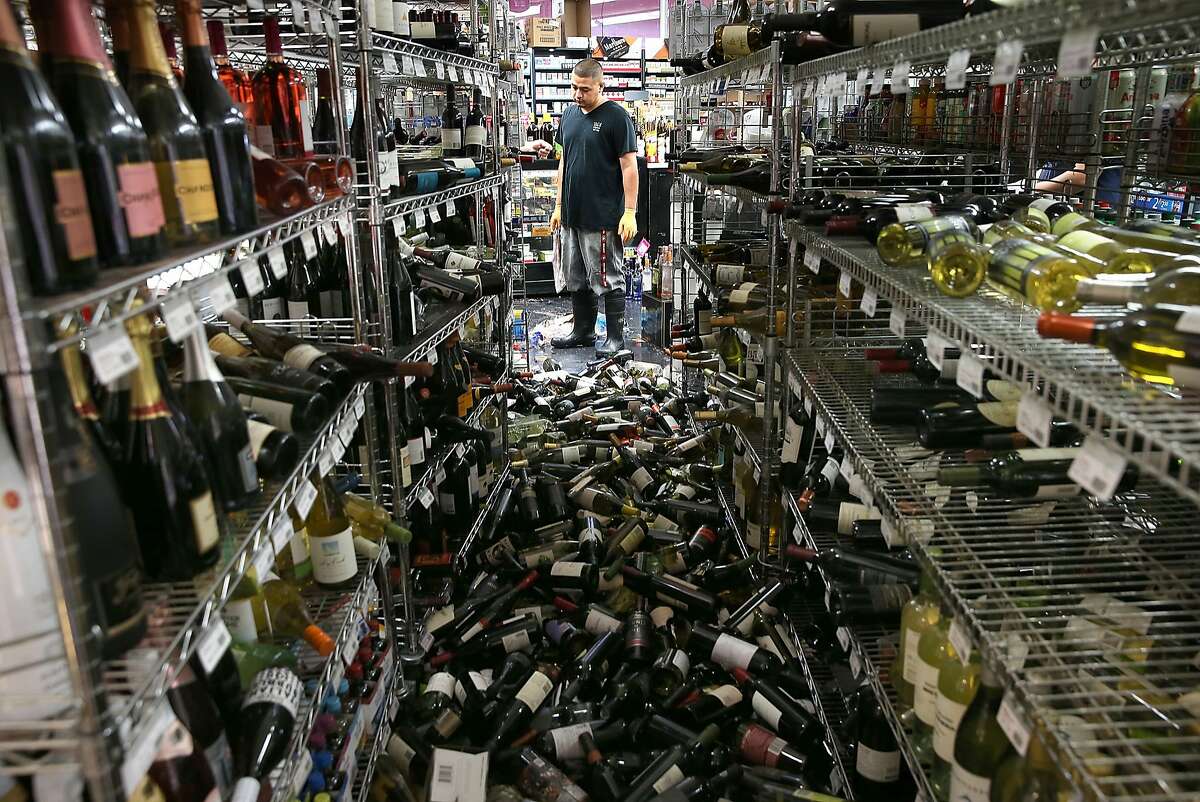 A worker looks at a pile of wine bottles that were thrown from the shelves at Van's Liquors following a 6.0 earthquake on Aug.24, 2014, in Napa.