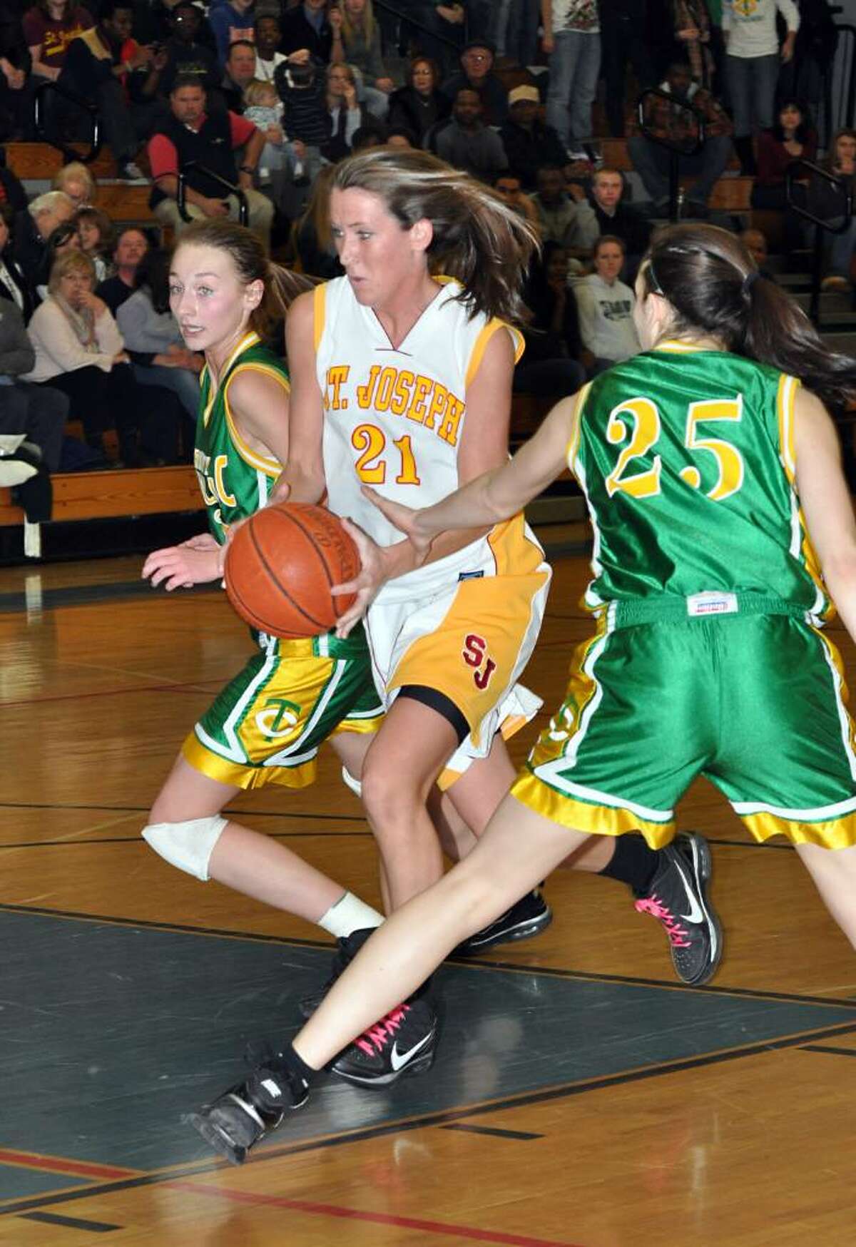 St. Joseph's Michele Gorman breaks through Trinity's defense Machkenzie Griffin and Ali Palma during the first half of the FCIAC girls basketball championship game at Fairfield Ludlowe High School on Saturday, Feb. 27, 2010.