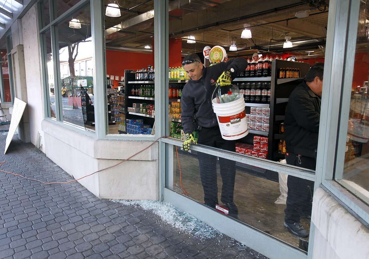 A restoration crew cleans up broken glass at the BevMo store at Jack London Square in Oakland, Calif. on Friday, Dec. 26, 2014 after vandals smashed storefront windows and damaged a decorated tree on Christmas night.