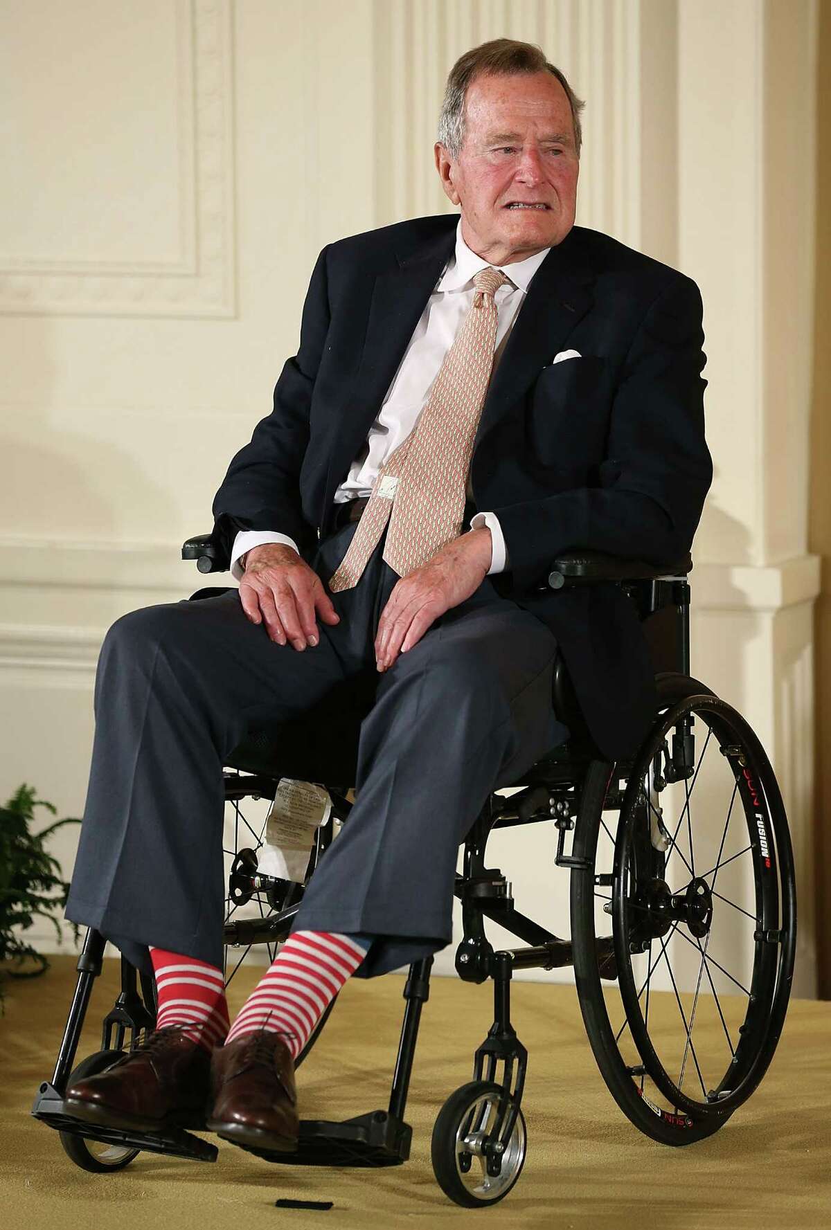 FILE - DECEMBER 24, 2014: It was reported that former U.S. President George H.W. Bush was hospitalized after experiencing a shortness of breath December 24, 2014 in Houston, Texas. WASHINGTON, DC - JULY 15: Former President George H. W. Bush wears red stripped socks as he sits in a wheelchair during an event in the East Room at the White House, July 15, 2013 in Washington, DC. Bush joined President Obama in hosting the event to honor the 5,000th Daily Point of Light Award winner. (Photo by Mark Wilson/Getty Images)