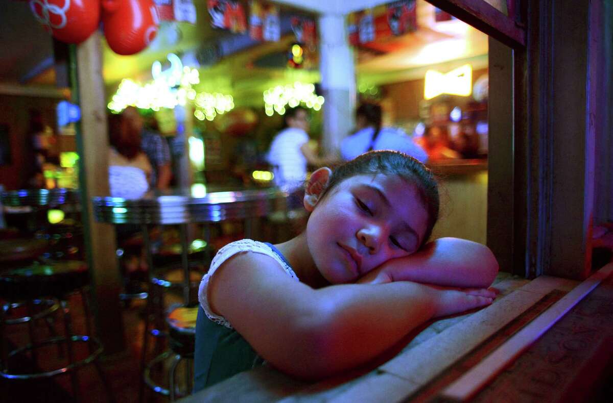Courtney Carreon relaxes as her mother, Michelle Hernandez, tends bar at Hernandez Ice House on West Mitchell on Saturday, Aug. 16, 2014.
