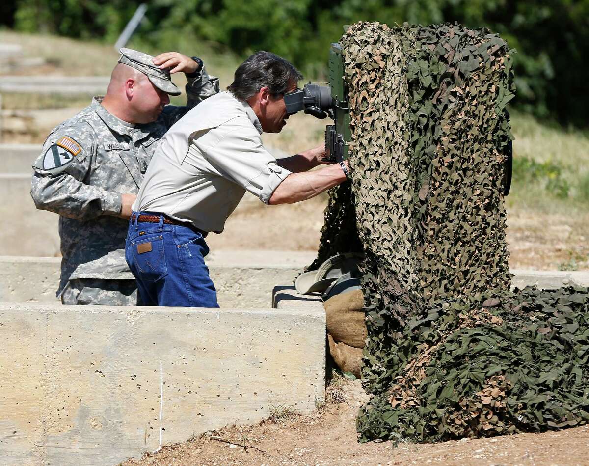 Texas Gov. Rick Perry examines an advanced optics system Wednesday Aug. 13, 2014 at Camp Swift near Bastrop that could be used by Guard troops when they deploy to the border.