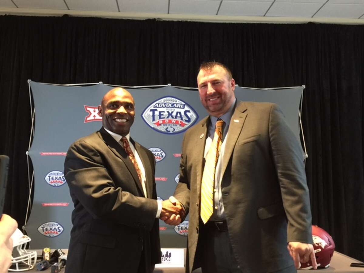 Arkansas coach Bret Bielema and Texas coach Charlie Strong shake hands at a press conference for the Texas Bowl on Saturday, and Bielema appears to be giving the "horns down" with his other hand, Saturday, December 27, 2014. (photo credit: Aaron Peters NBC KARK (Little Rock) / KNWA (northwest ark)) (@aaronpetersrn)