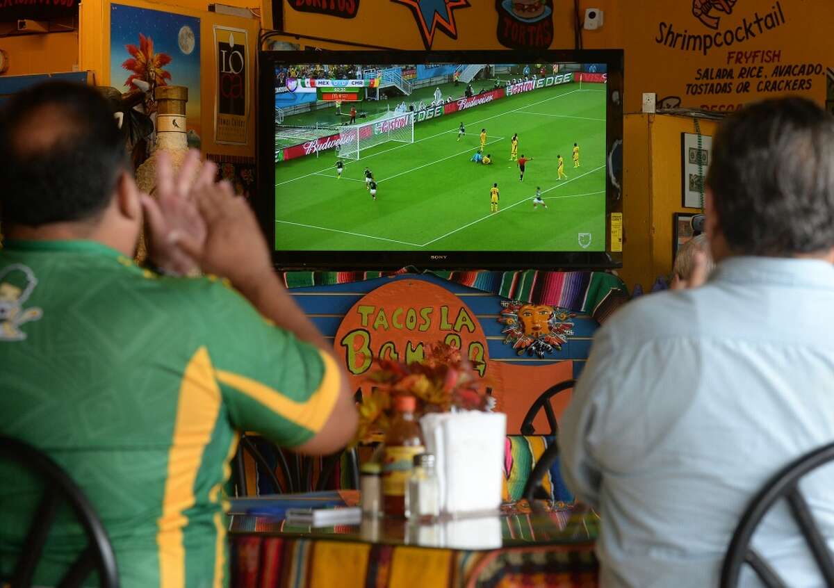 From left, Samuel Gallego and Carlos Sunea cheer at Tacos La Bamba in Beaumont while watching Mexico score against Cameroon in the World Cup on Friday. Photo taken Friday, June 13, 2014 Guiseppe Barranco/@spotnewsshooter
