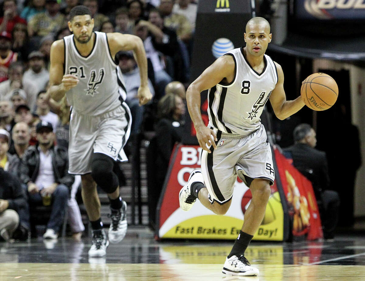 The Spurs’ Patty Mills brings the ball upcourt as Tim Duncan follows behind during the second half against Houston at the AT&T Center on Dec. 28, 2014. The Spurs beat the Rockets 110-106.