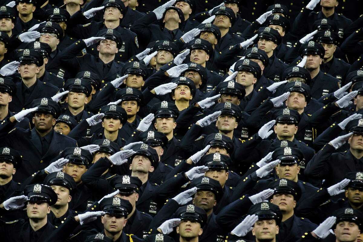 New recruits raise their heads and salute in honor of deceased officers Rafael Ramos and Wenjian Liu during a New York Police Academy graduation ceremony, Monday Dec. 29, 2014, at Madison Square Garden in New York. Nearly 1000 officers were sworn in as tensions between city hall and the NYPD continued following the Dec. 20 shooting deaths of officers Ramos and Liu. (AP Photo/John Minchillo) ORG XMIT: NYJM101