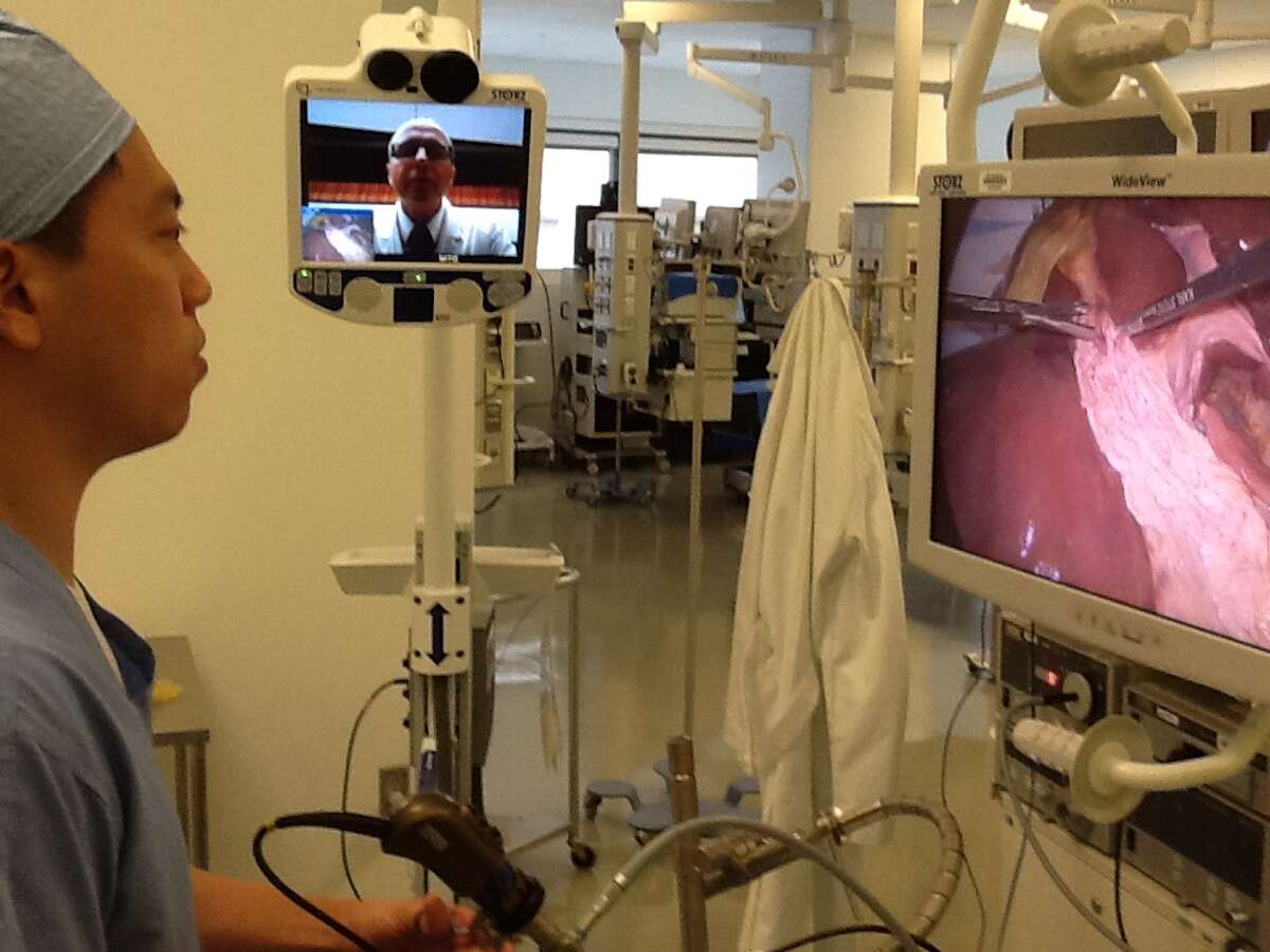 Houston Methodist surgical resident Dr. Albert Huang, left, listens as Dr. Brian Dunkin, medical director at the Houston Methodist Institute for Technology, Innovation and Education, uses telementoring technology to instruct Huang during a simulated operation.