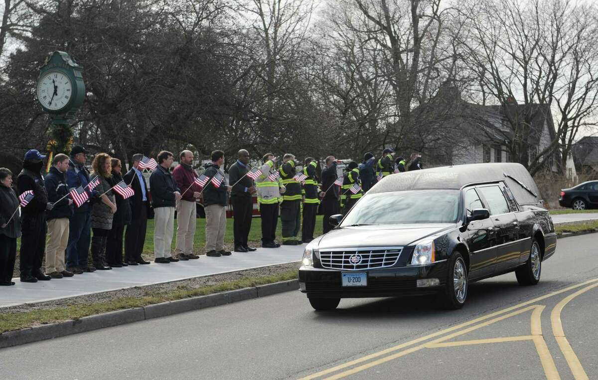The funeral procession of Greenwich Selectman David Theis passes by Town Hall in Greenwich, Conn. Tuesday, Dec. 30, 2014. Friends, family and colleagues at Town Hall stood outside with American flags as the procession passed by before noon on Tuesday. Theis died unexpectedly on Dec. 23 at the age of 65 after many years serving the Town of Greenwich and five years as selectman.