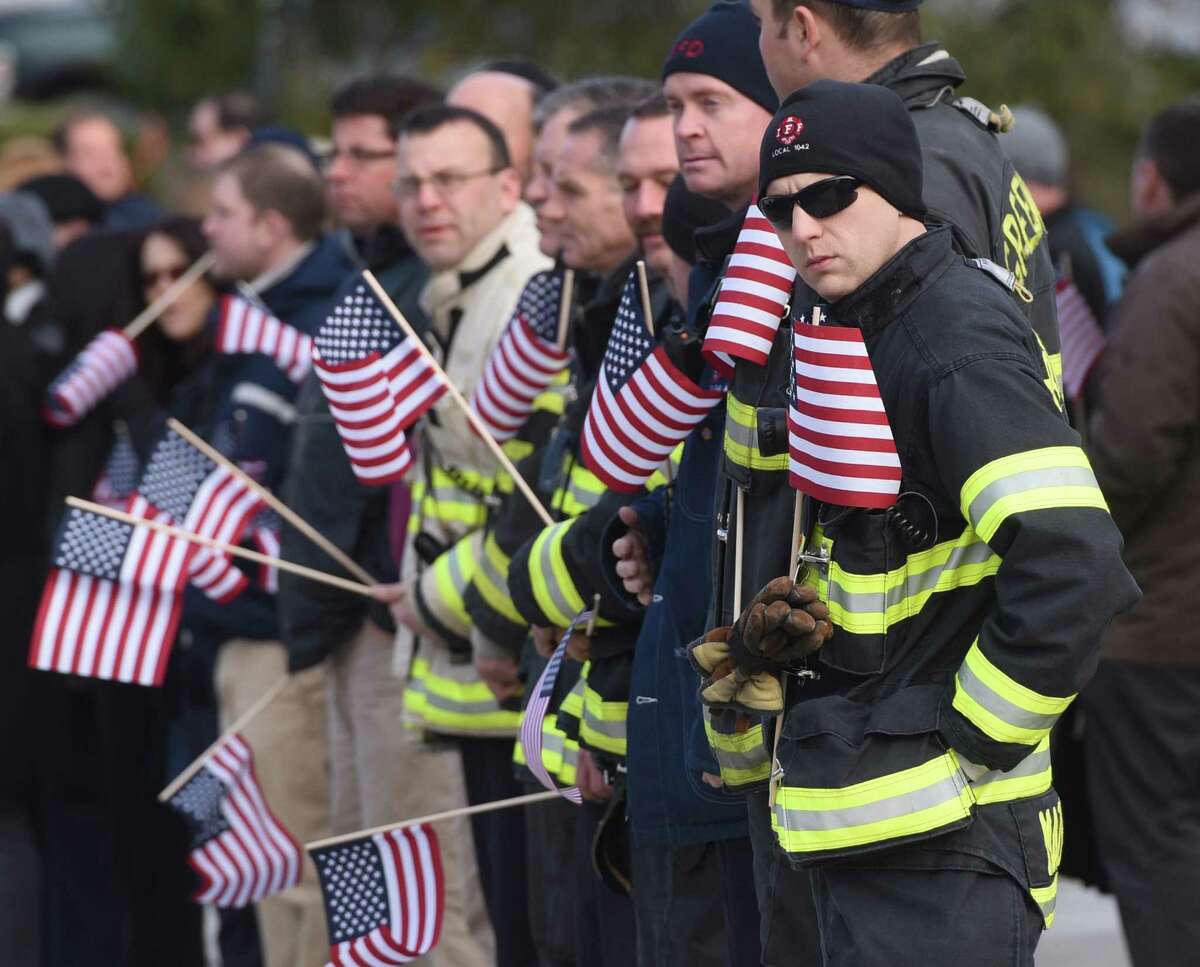 Erik Maziarz and other members of the Greenwich Fire Department gather outside for funeral procession of Greenwich Selectman David Theis at Town Hall in Greenwich, Conn. Tuesday, Dec. 30, 2014. Friends, family and colleagues at Town Hall stood outside with American flags as the procession passed by before noon on Tuesday. Theis died unexpectedly on Dec. 23 at the age of 65 after many years serving the Town of Greenwich and five years as selectman.