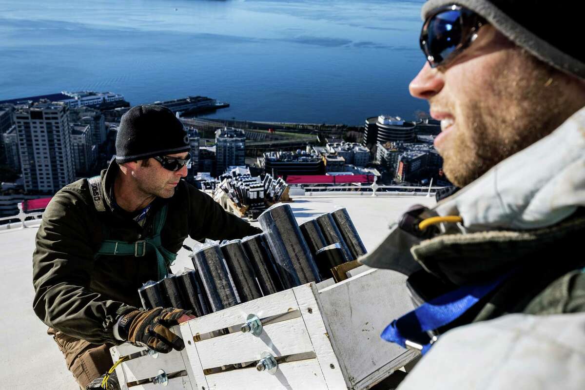 Scott Streeper, left, and Kevin Gilfillan, right, of Pyro Spectaculars work to install several thousand pyrotechnic shots on the roof of the Space Needle for the upcoming, eight-minute T-Mobile New Years at the Needle fireworks display, photographed Tuesday.