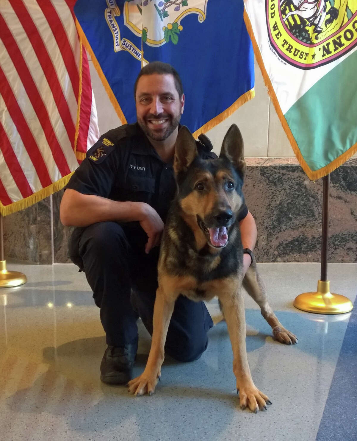 Officer Michael Macchia and his canine partner Tyro pose in the lobby of the Greenwich Police Department headquarters Thursday, Tyro's last day on the job after a seven-year career.