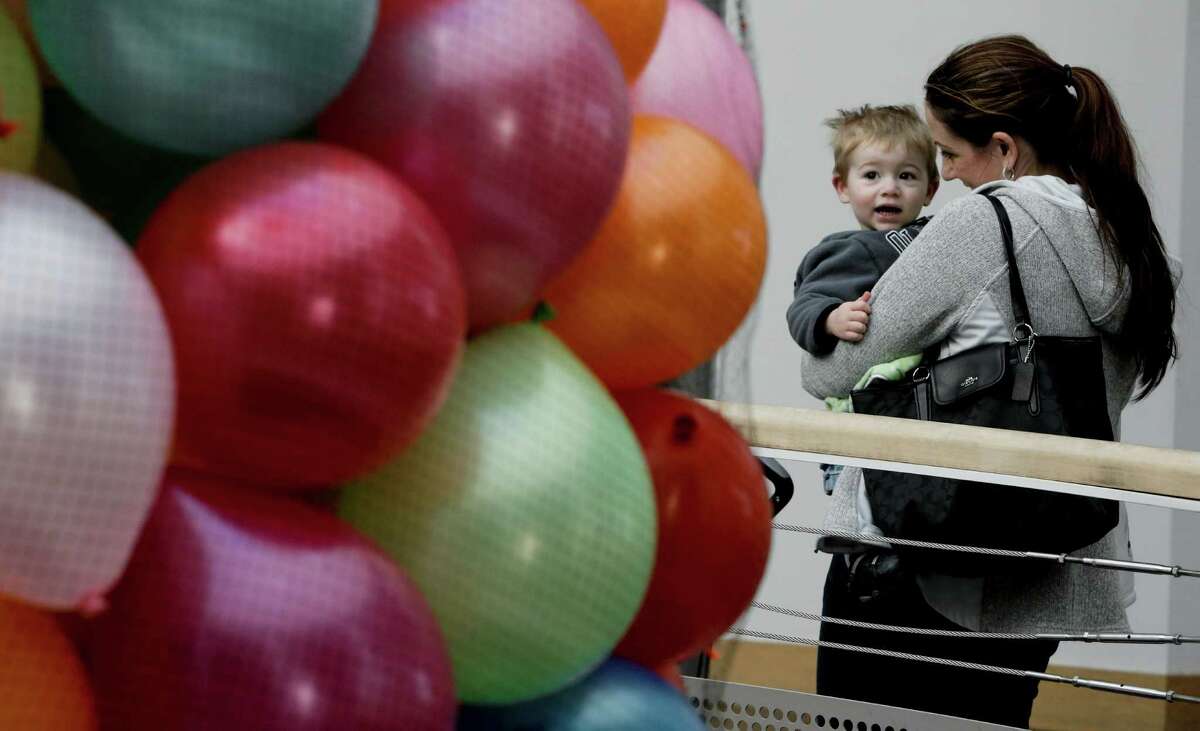 Catherine Ratshin and her 1-year-old son, Emmett, of Sacramento look over a net full of balloons as Oakland’s Chabot Space & Science Center celebrates the stroke of midnight around the world with a balloon drop.