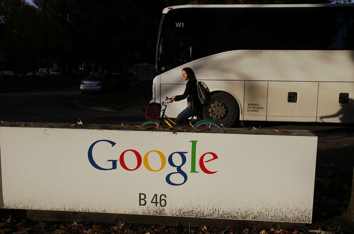 An employee rides a Google bike as a Google bus drives past the Google sign at Google's Mountain View headquarters Dec. 4, 2014 in Mountain View, Calif.