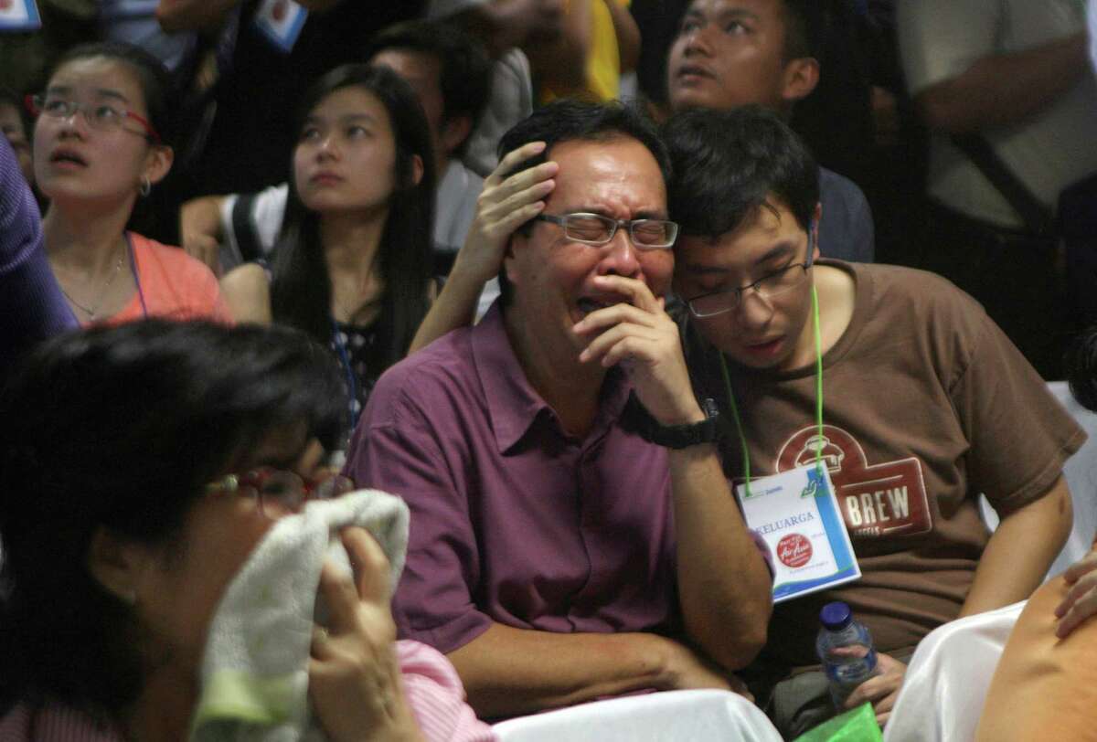 Relatives of passengers of the missing AirAsia Flight 8501 react upon seeing the news on television about the findings of bodies on the waters near the site where the jetliner disappeared, at the crisis center at Juanda International Airport in Surabaya, East Java, Indonesia, Tuesday, Dec. 30, 2014. Bodies and debris were seen floating in Indonesian waters Tuesday, painfully ended the mystery of AirAsia Flight 8501, which crashed into the Java Sea and was lost to searchers for more than two days.