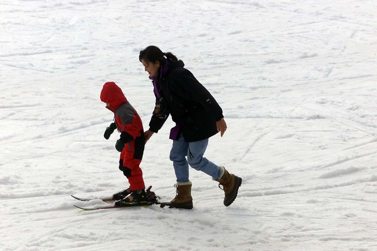 A woman gives a young child a helping hand as they head towards the "Turtle" run at Yosemite National Park's Badger Pass ski resort on a sunny winter day.