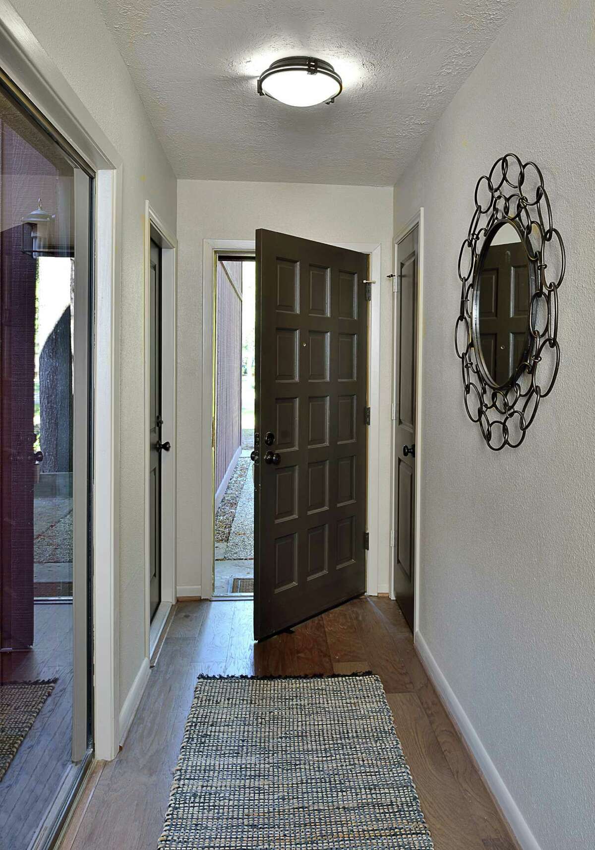 The front door was refinished with a dark stain, and wood floors replaced Spanish tile in the entryway and throughout the main living areas.