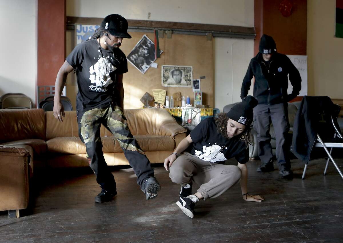 Khafre James the executive director and founder of "Hip Hop For Change" demonstrates a few break dancing moves to Jada Carter, 16 a former student of the hip hop course taught by James' organization, at their offices in Oakland, Calif., as seen on Wednesday Dec. 31, 2014. Malik Diamond, a team member of Hip Hop For Change is seen at right.
