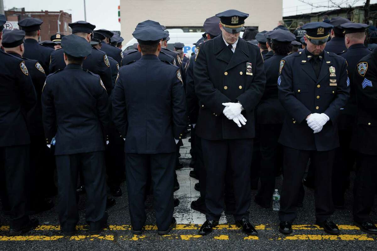 Some police officers, left, turn their backs in a sign of disrespect as Mayor Bill de Blasio speaks as others, at right front line, stand at attention, during the funeral of New York Police Department Officer Wenjian Liu at Aievoli Funeral Home, Sunday, Jan. 4, 2015, in the Brooklyn borough of New York. Liu and his partner, officer Rafael Ramos, were killed Dec. 20 as they sat in their patrol car on a Brooklyn street. The shooter, Ismaaiyl Brinsley, later killed himself.