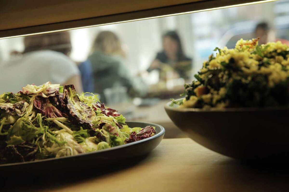 Customers enjoy lunch as seen through the display case at Seed + Salt in San Francisco.