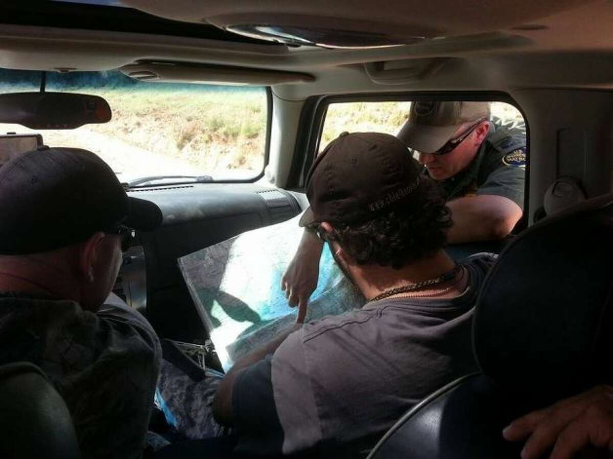 Militia members look at a map and talk with someone who appears to be a Border Patrol agent. Militia groups have gathered on the Texas-Mexico border from El Paso to the Rio Grande Valley.