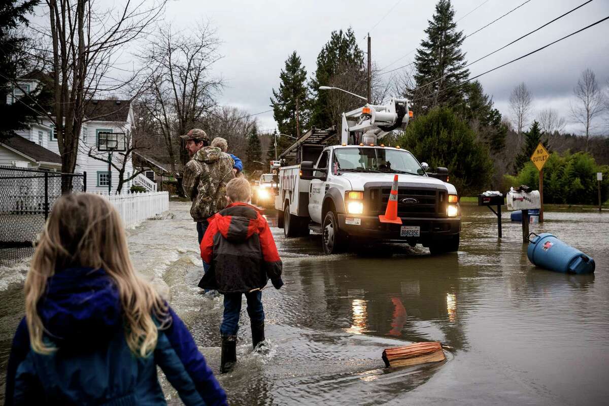 Families walk through a heavily-flooded neighborhood on the banks of the Snoqualmie River Monday, January 5, 2015, in Snoqualmie, Washington. Floods and landslides closed several roads and forced evacuations across Western Washington following a heavy storm in the early morning.
