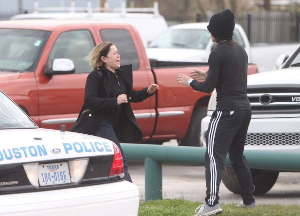 A woman reacts at the scene of a north Houston car lot shooting that left two dead and sent another to a hospital on Thursday, Jan. 8, 2015.