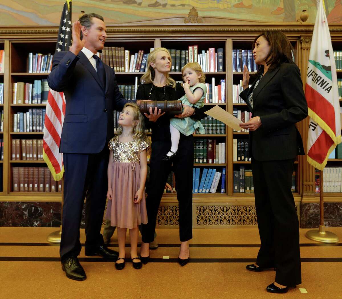 Montana Newsom, 5, second from left, looks up at her father, Lt. Gov. Gavin Newsom, as he takes the oath of office from Attorney General Kamala Harris, right, during an inauguration ceremony in Sacramento, Calif., Monday, Jan. 5, 2015. Along with Montana, Newsom was accompanied by his wife, Jennifer, and daughter Brooklynn,1.