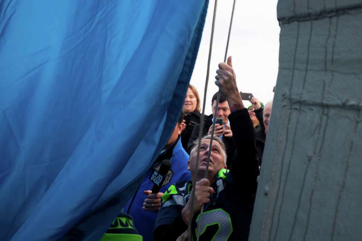 In celebration of the Seahawks playoff game, Pearl Jam lead guitarist, Mike McCready, raises the 12th man flag on the roof of the Space Needle at 9 a.m. on Friday, January 9, 2015.