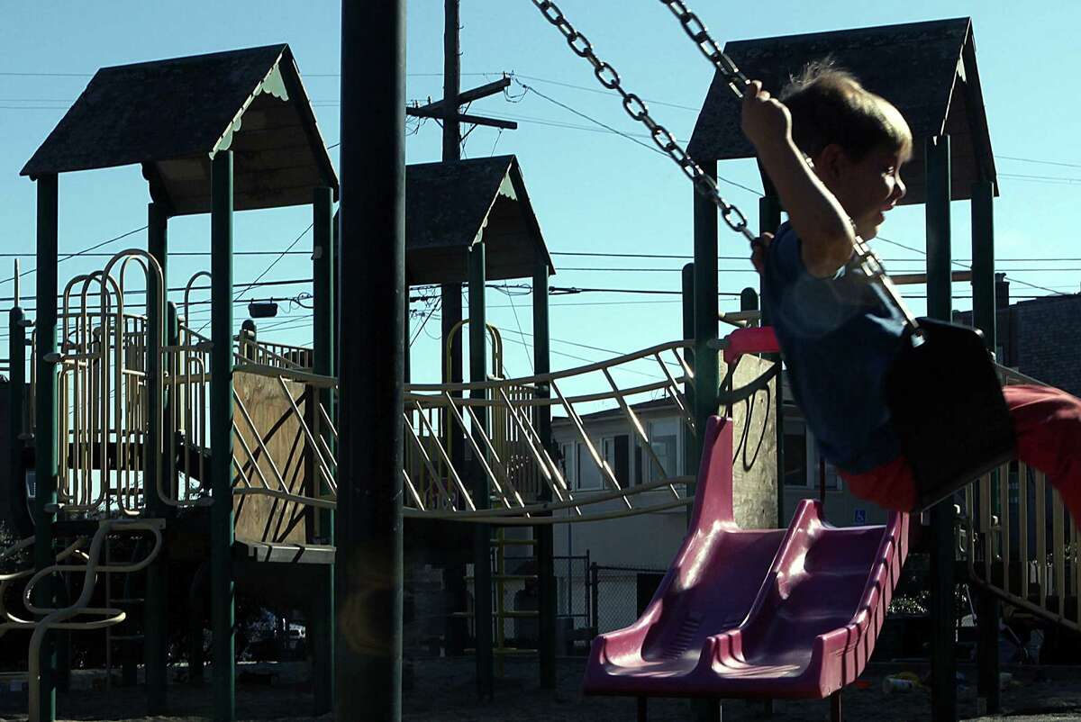 A child swings near a bridge that has been boarded up on a play structure at Douglass Park for six months.