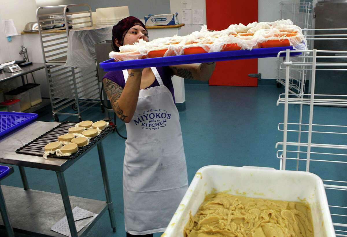 Production assistant Cori Ander, left. readies High Sierra Rustic Alpine cheese to be aged at Miyoko's kitchen in Fairfax, Calif., on Tuesday, December 30, 2014.