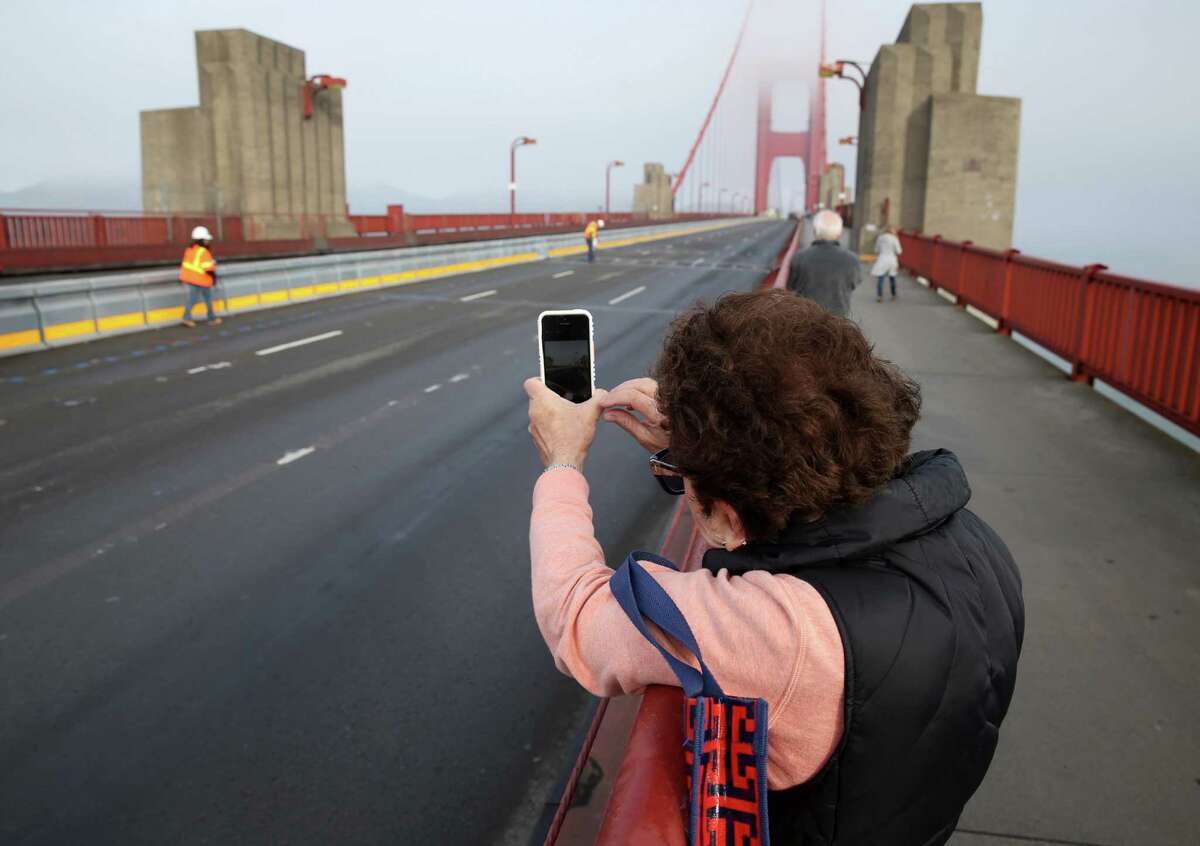 Lynn Bloom snaps a photo of a road crew installing the movable median barrier on the Golden Gate Bridge in San Francisco, Calif. on Saturday, Jan 10, 2015. 