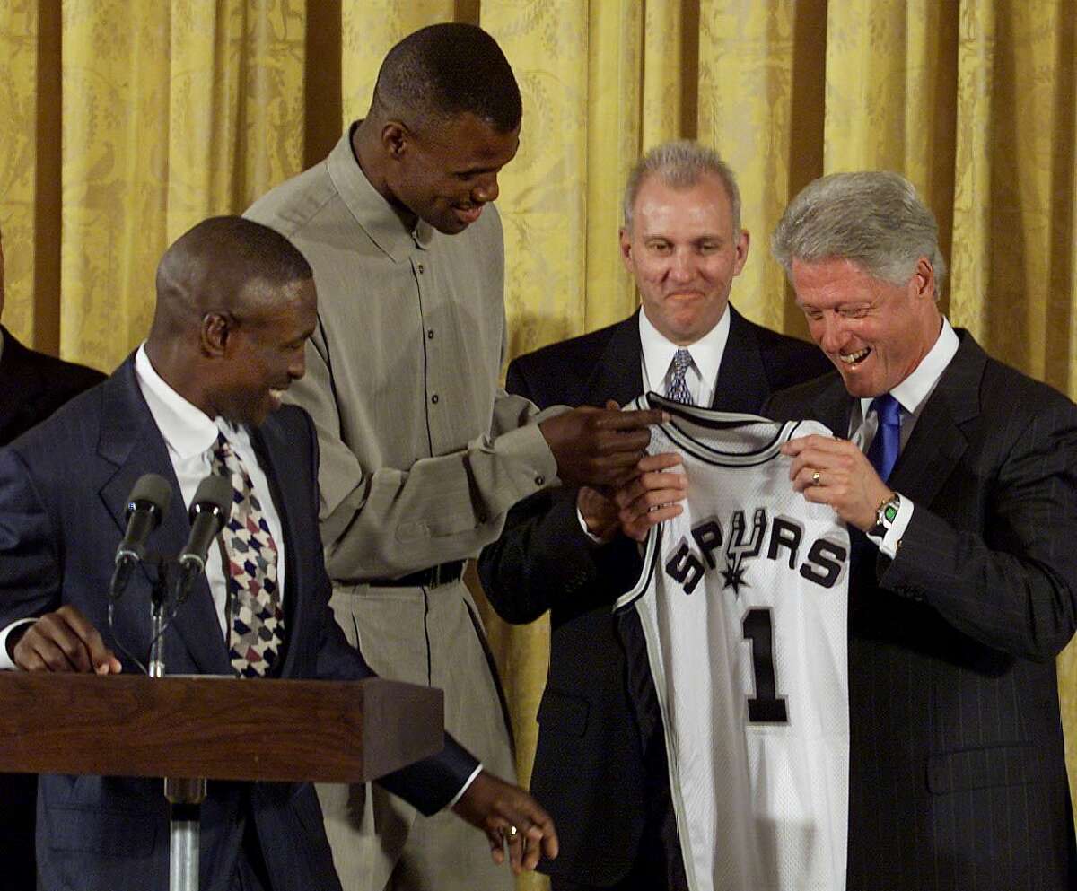 WASHINGTON, : US President Bill Clinton (R) is presented with a San Antonio Spurs team jersey 07 September, 1999, by Spurs players David Robinson (2nd-L) and Avery Johnson (L) as coach Gregg Popovich (2nd-R) looks on at the White House in Washington, DC. The Spurs won the 1999 NBA Championship and were the guest of President Clinton at the White House. (ELECTRONIC IMAGE) AFP PHOTO Luke FRAZZA (Photo credit should read LUKE FRAZZA/AFP/Getty Images)