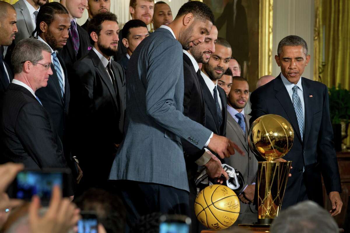 President Barack Obama looks at the Larry O'Brien Championship Trophy during a visit by the San Antonio Spurs at a ceremony recognizing their 2014 NBA championship in the East Room of the White House in Washington, Jan. 12, 2015.