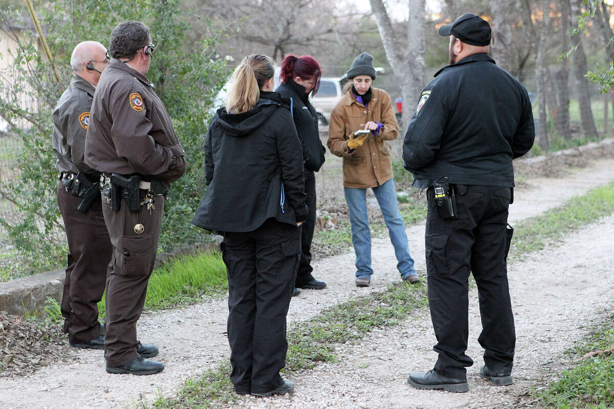 Officer Annamarie Cozzi of Animal Care Services, third from left, with Bexar County Constables, left, and other officers from ACS discuss a situation with a citizen, second from right, in the 1400 block of Creek View on Cozzi's night shift rounds Dec. 23.