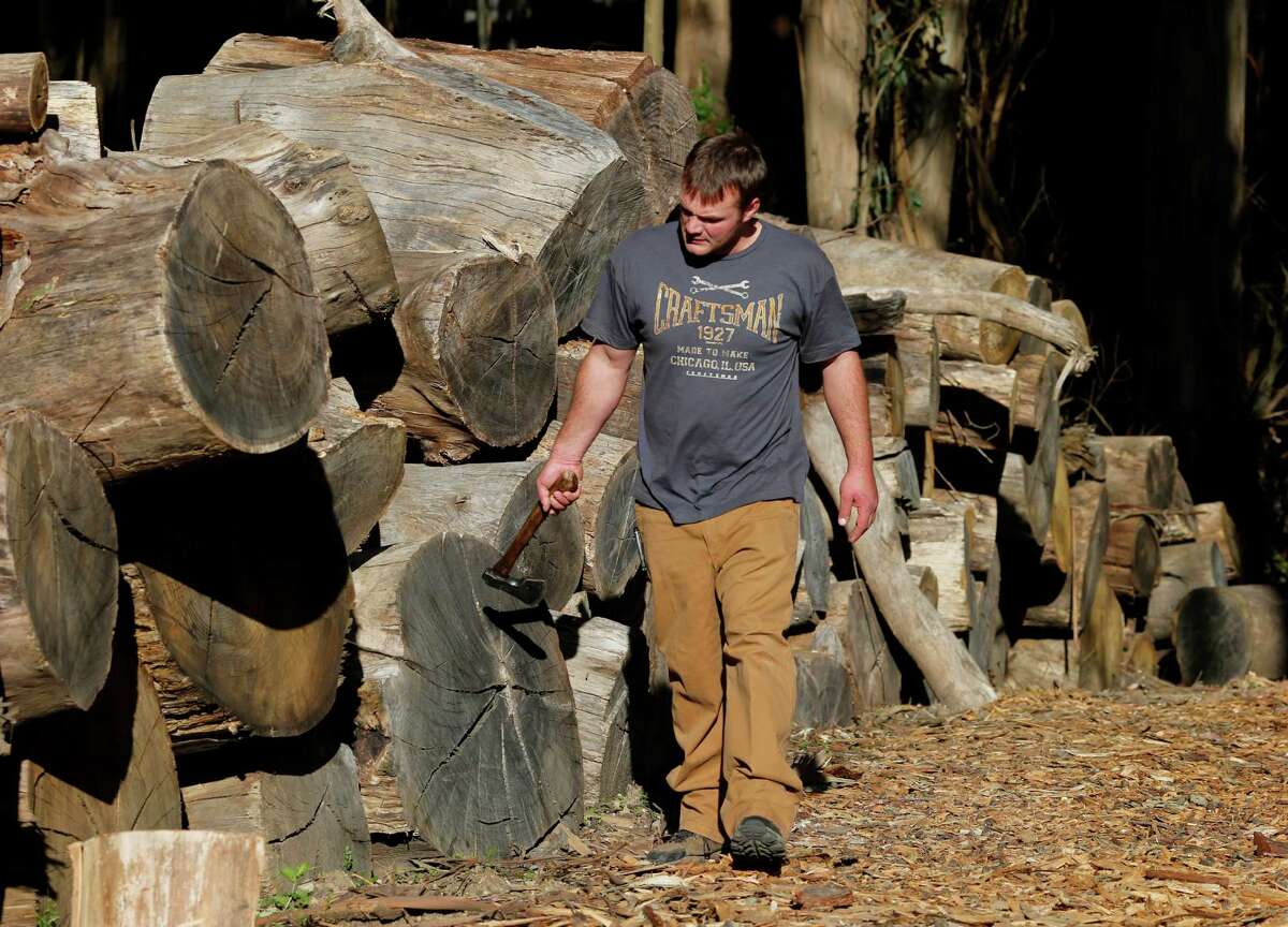 James Olsen walks near eucalyptus wood he hopes to sell on Monday. Olsen of Firewood Farms has seen a 70 percent drop in firewood sales because of the record number of Spare the Air days this year at his Half Moon Bay recycled wood business.