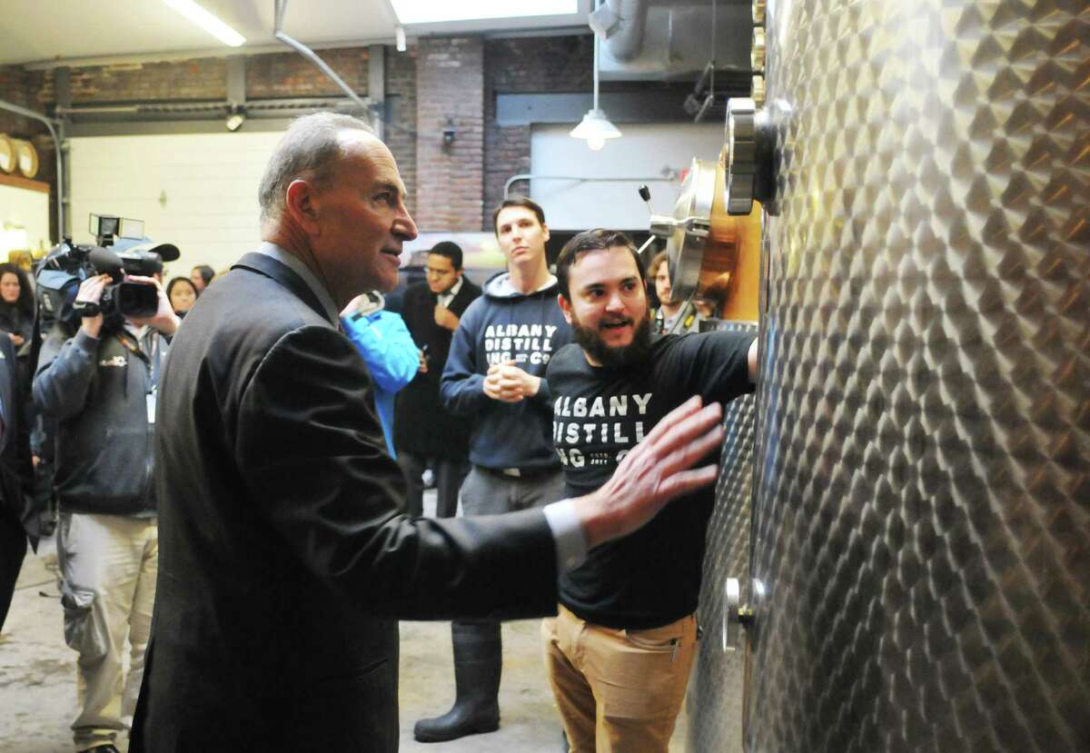 Senator Charles Schumer, left, looks over the equipment at the Albany Distilling Company as he gets a tour from owners John Curtin, right, and Rick Sicari, background, on Monday, Jan. 12, 2015, in Albany, N.Y. Senator Charles Schumer held a press event at the distillery to push for crop insurance for New York State malt barley farmers. (Paul Buckowski / Times Union)